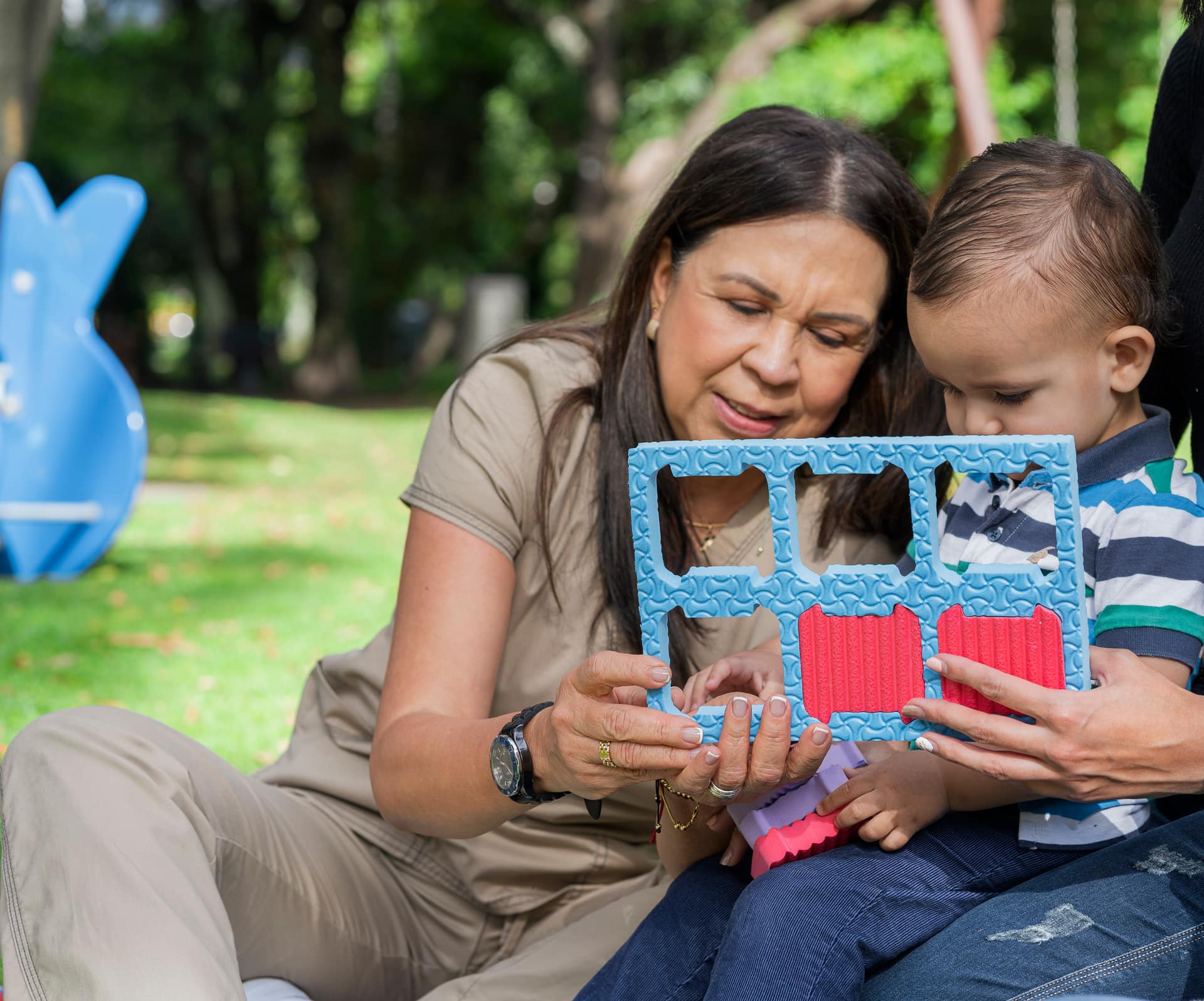 Behavior technician guiding a toddler through a shape puzzle during an outdoor early intervention therapy session