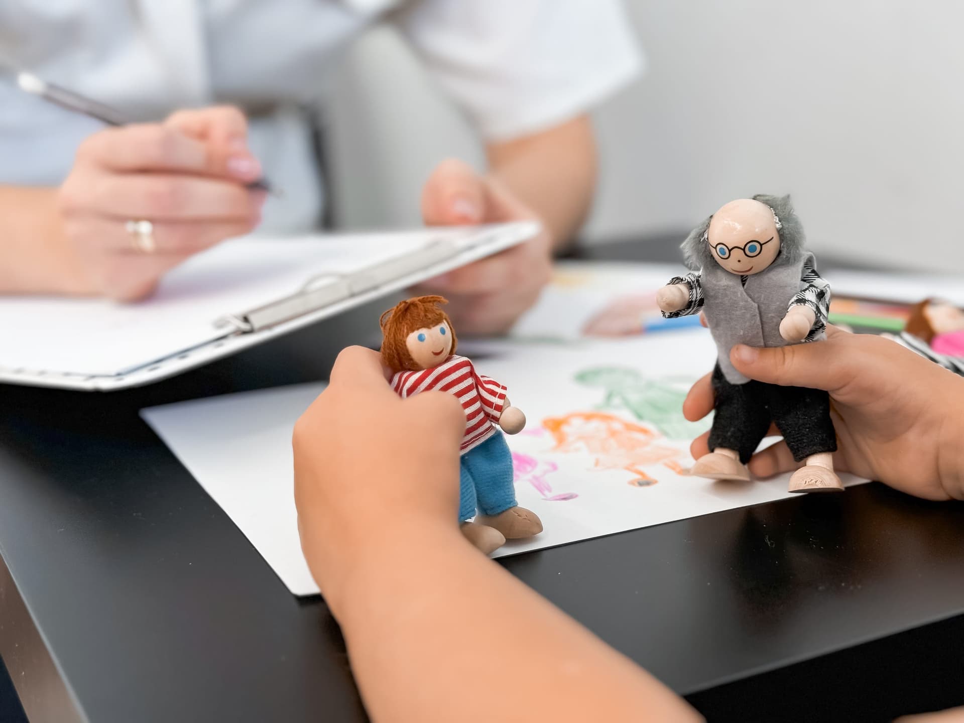 Niño participando en una evaluación ABA basada en el juego con figuritas mientras un clínico toma notas