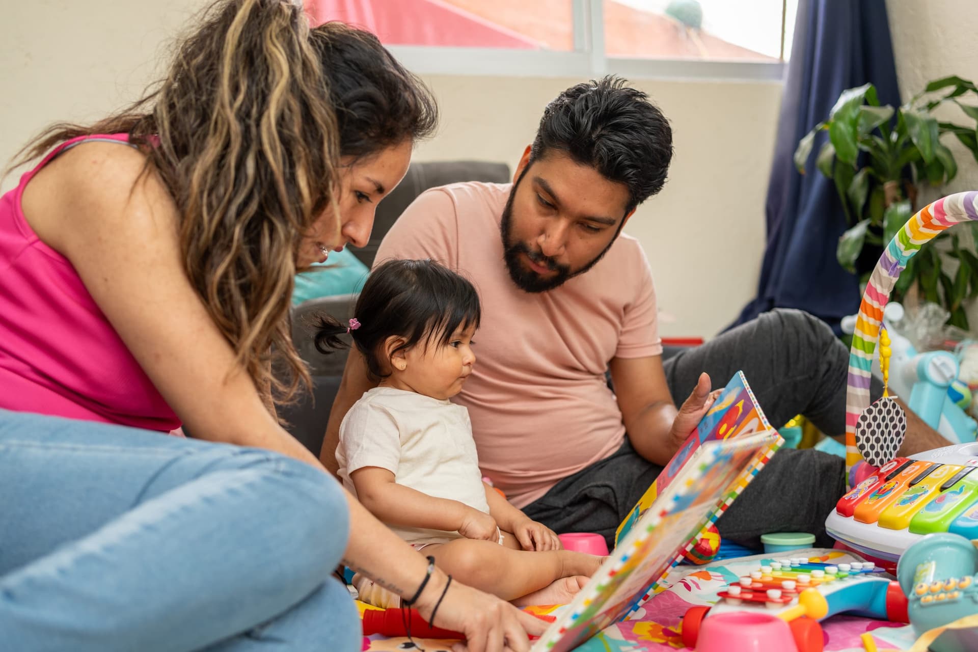 Padres hispanos participando en capacitación de juego con su bebé en casa como parte de la terapia ABA