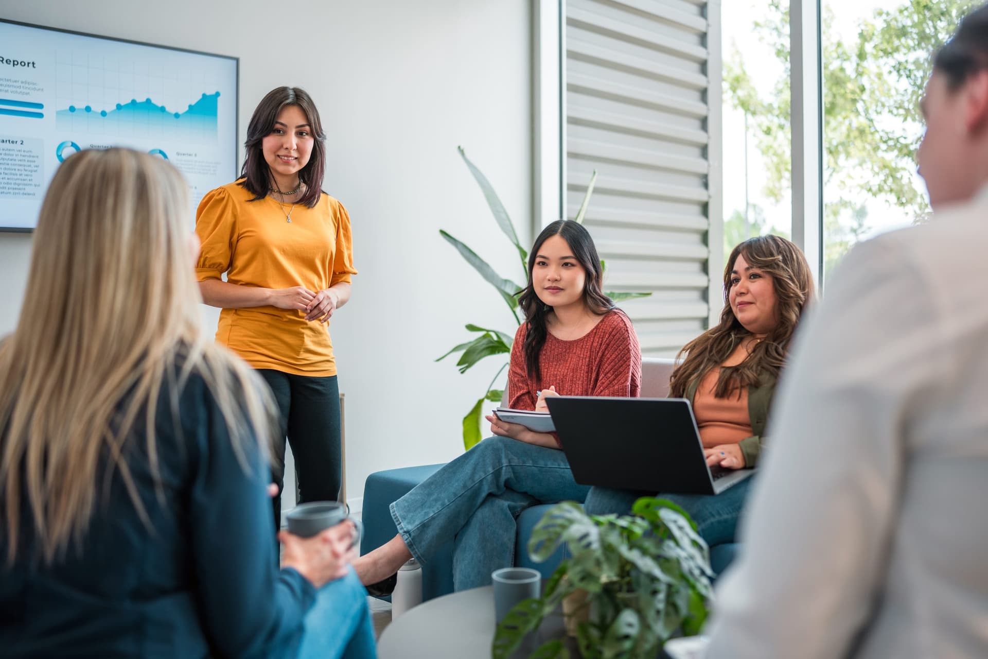 A behavior analyst presents clinical data on a screen to a diverse team of colleagues in a modern collaborative workspace