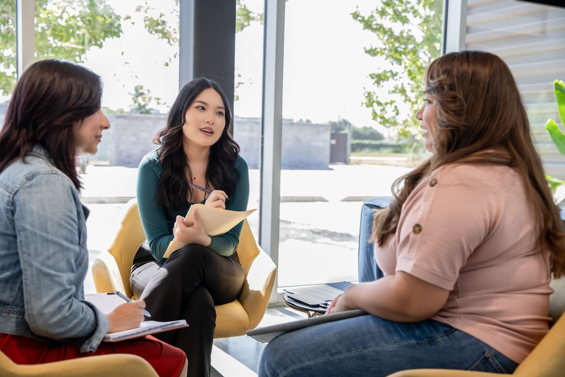 Clinical supervisor leading a team meeting with two behavior analysts, reviewing treatment documentation in a collaborative workspace